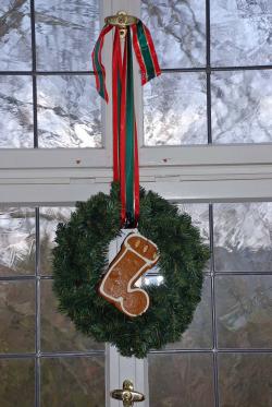 Das Foto zeigt einen Kranz mit Schleifen und einem Nikolausstiefel in der Mitte vor einem Schlossfenster. (Foto: OBK)