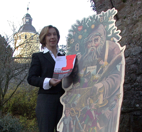 Museumsleiterin Dr. Gudrun Sievers-Flägel mit dem Plakat des Nikolausmarktes 2006 vor der Schlosskulisse in Nümbrecht