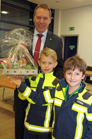 Die Mitglieder der Kinderfeuerwehr Bergneustadt Niklas Mießner (r.) und Malte Rothkamm bedankten sich mit einem leckeren Weihnachtsgeschenk bei Landrat Jochen Hagt. (Foto: OBK) 