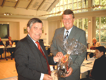 Das Bild zeigt Landrat Hagen Jobi, der dem Regierungspräsidenten zur Erinnerung an den Oberbergischen Kreis eine Dröppelminna schenkt.