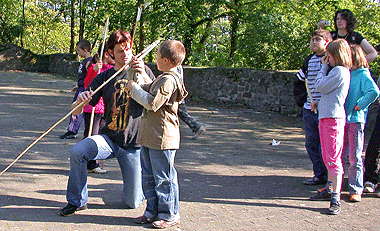 Das Foto zeigt Schülerinnen und Schüler beim Ausprobieren des Wurfspeers auf dem Gelände von Schloss Homburg.