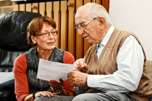 Betreuerin spricht mit älterem Mann über ein Schriftstück (Foto: Adobe Stock/Ingo Bartussek)