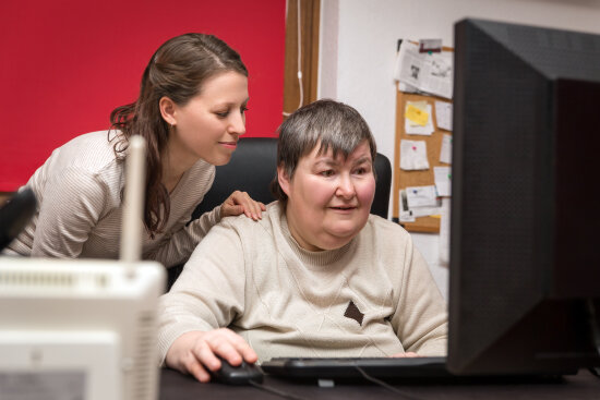 Betreuerin hilft Frau mit Behinderung bei der PC-Arbeit (Foto: Adobe Stock/M.Dörr & M.Frommherz)