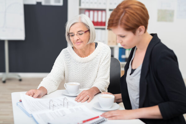 Jüngere Frau arbeitet unterstützt ältere Frau bei Anträgen. (Foto: Adobe Stock/contrastwerkstatt)