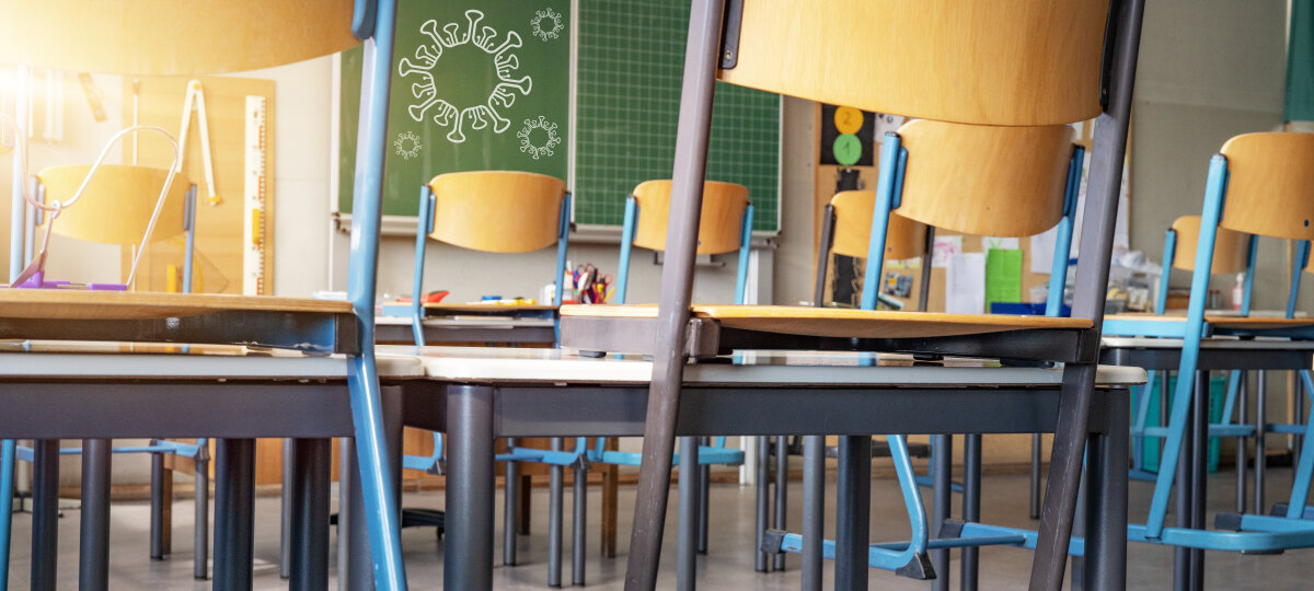 CORONAVIRUS - School closed - Empty classroom with high chairs and empty green blackboard / chalkboard with cartoon virus symbol
