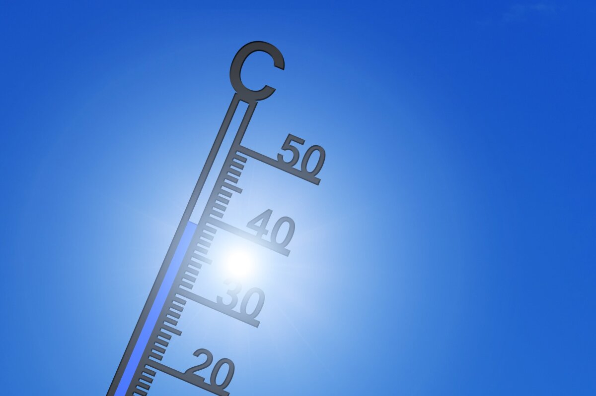 Thermometer vor Sonne am blauen Himmel