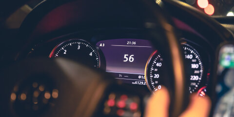 Speed indication and women's hands on the steering wheel in a car at night.