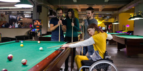 Disabled girl in a wheelchair playing billiards