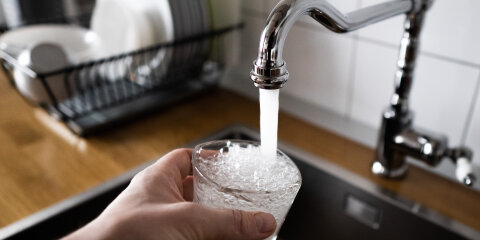 male's hand pouring water into the glass from chrome faucet to drink running water with air bubbles. potable water and safe to drink. man filling a glass of water from a stainless steel kitchen tap.