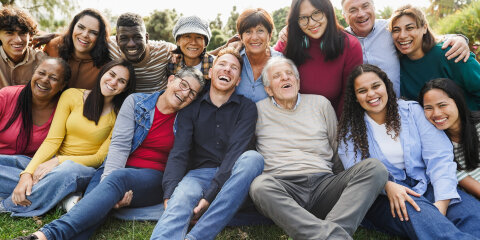 Group of multigenerational people smiling in front of camera - Multiracial friends of different ages having fun together - Main focus on senior man face